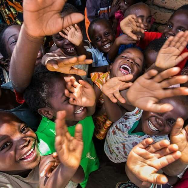 Joyful African children laughing and waving hands with pure hope and resilience